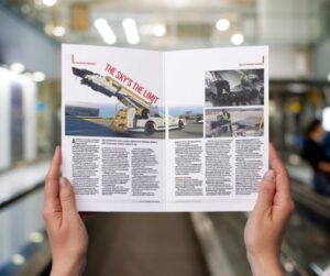 Hands holding a groundhandlinginternational magazine with a belt loader and tail loader