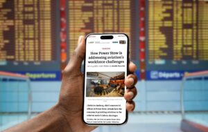 A smartphone displaying the Airside International article “How Power Stow is addressing aviation’s workforce challenges”, photographed in an airport setting.