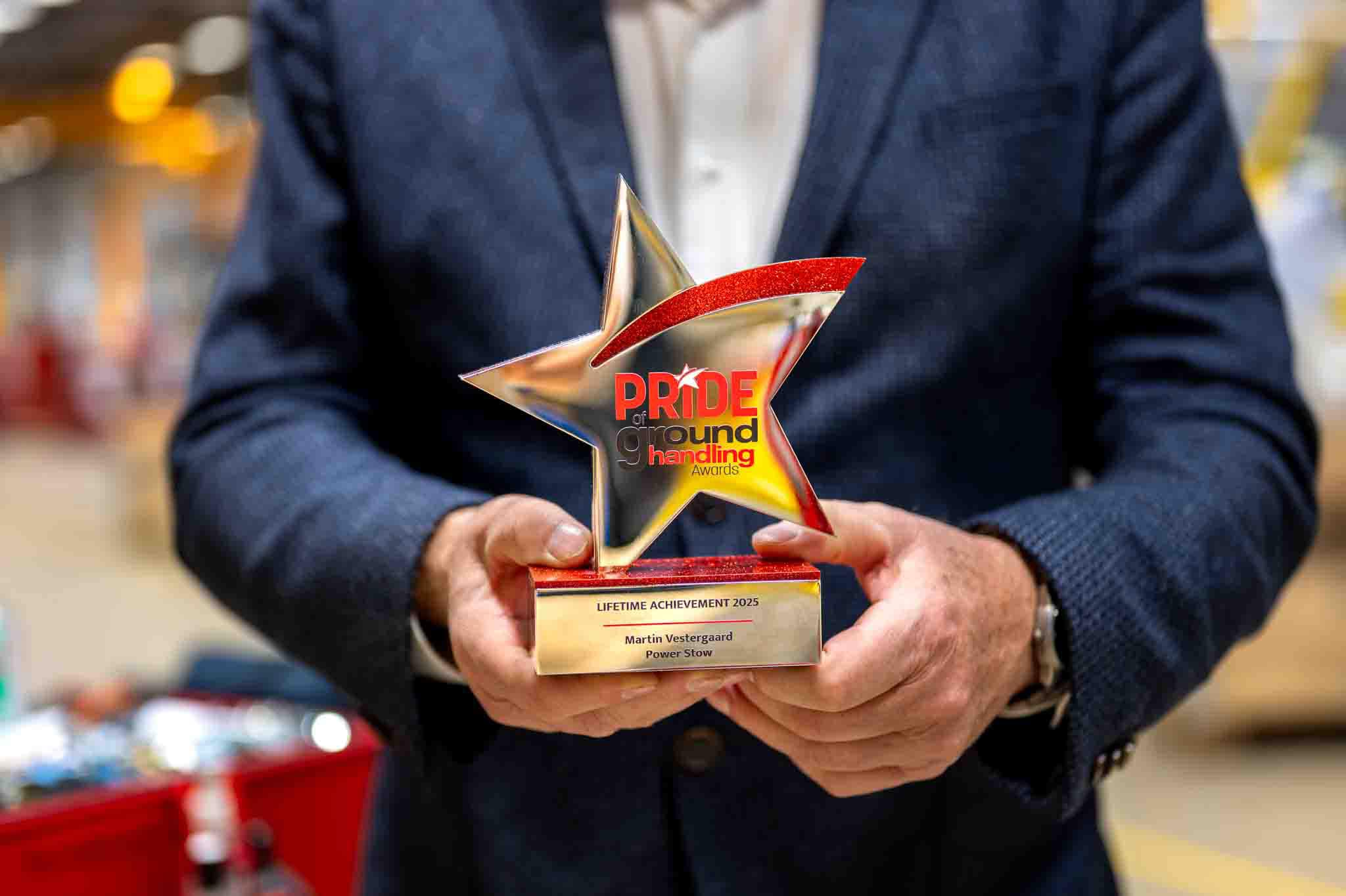 Close-up of Martin Vestergaard holding the Pride of Ground Handling Awards 2025 lifetime achievement trophy, with the star-shaped award clearly visible.